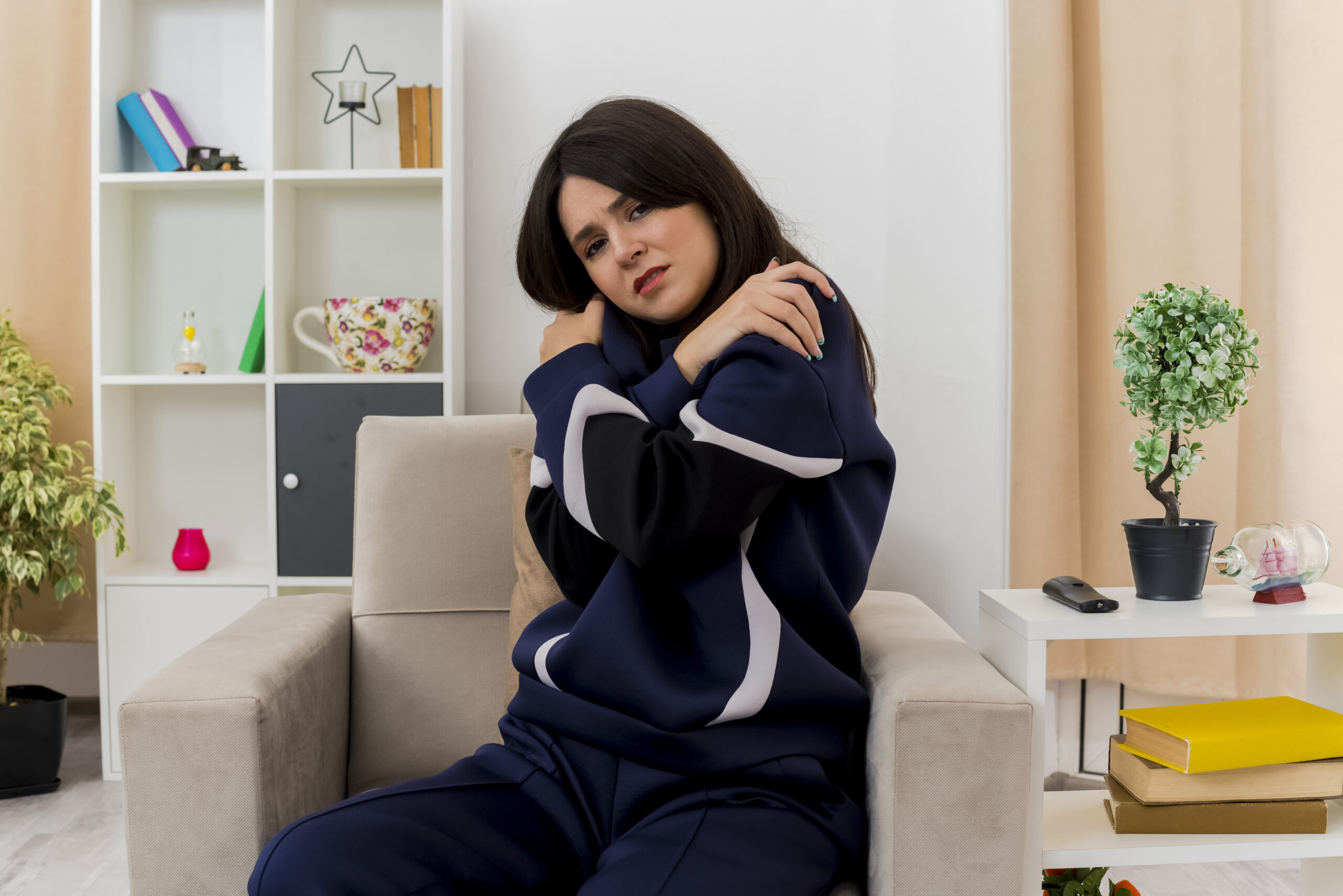 cold young pretty caucasian girl sitting on armchair in designed living room keeping hands crossed and putting them on shoulders looking at camera SSUCv3H4sIAAAAAAAACpyRy24DIQxF95X6DyPWGWleyZT+StSFAWcGhUAETKsqyr+XxxCx7g4f29e+5vH+1jSEgZOcfDaPGIVYKrU5b8FLowPuDju3qAXamqCQ3lgJqoYMPF813DBAvSkV8TMlifPgN4cuDtsRB49L0MjwJZE3Oue4KYmUDB0hRcihYm5jiRWUxf/VmR9fxQ0sqPlvWrgyYlEhZCPnXEquPx7trbYGm5CmcvVtOKhYMFZKdyu51EvVZvyarlzauNm0t3GF1+ZEGXMHpuKJL0ETC1/BuVAuCq8G8fCn5lbN0cYnA7sqEeEnYtiPw0QHOnfd3NGPfp6Oe0H+vVUGnbROEQoxv0pRW5dxAzL3dKTDMLZwnC7tJDreMn6CFjuc2IlSPvQYDv/8AwAA//8DAJ1ojvqHAgAA