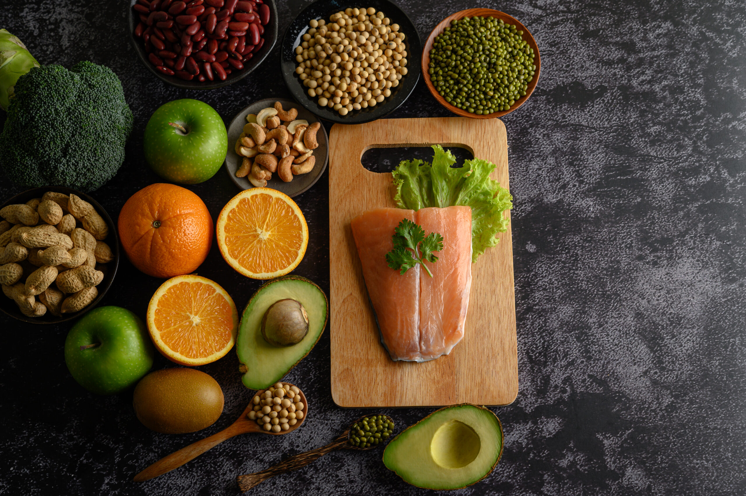 legumes, fruit, and Salmon fish pieces on a wooden chopping board.